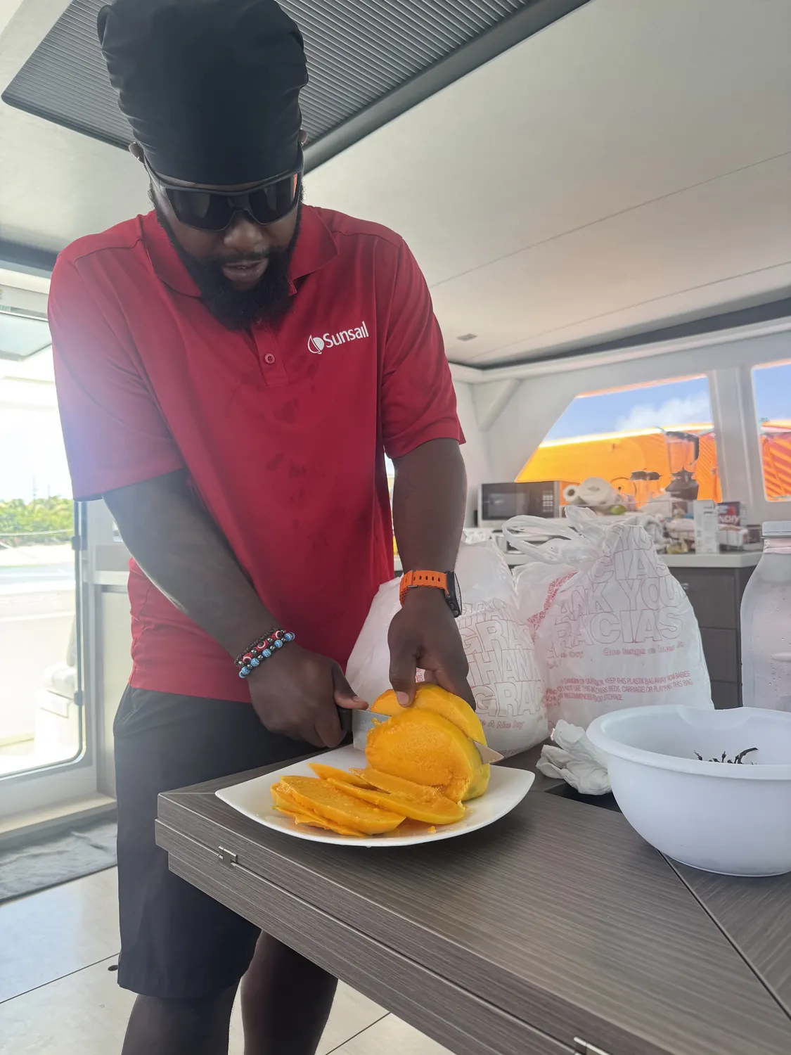 Captain Teno slicing fresh mango for guests aboard the catamaran