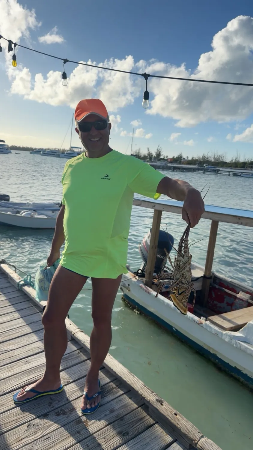 A guest on the dock holding a fresh-caught Caribbean spiny lobster